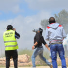 Press photographer takes picture as Palestinian protestor throws tear gas canister