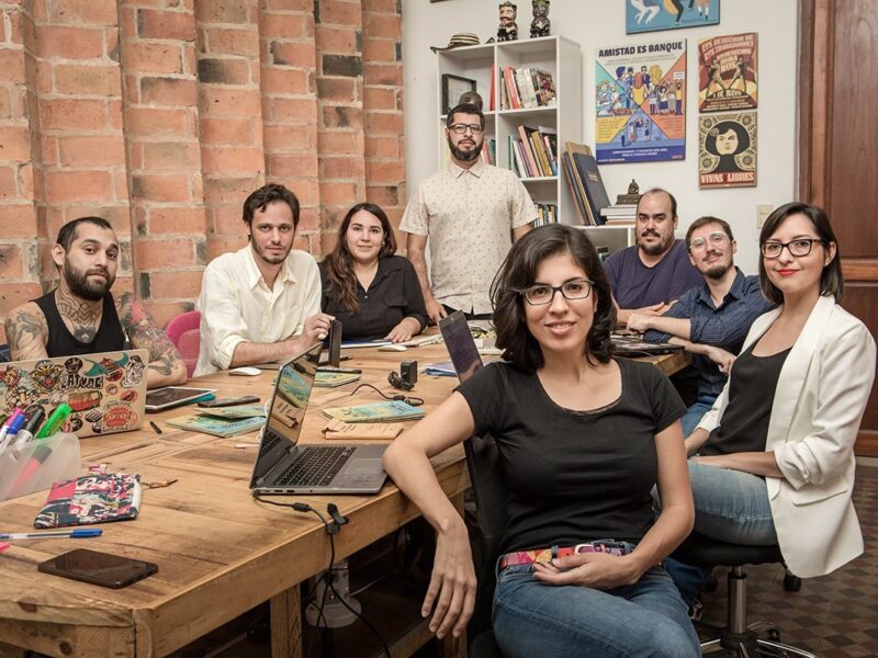 Fotografía de la sala de redacción de El Surtidor, con los cofundadores Alejandro Valdez (de pie en el centro) y Jazmín Acuña (de pie atrás). Imagen: cortesía de El Surtidor